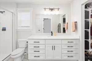 Bathroom featuring a shower with shower door, toilet, and vanity