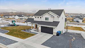 View of front of house with a playground, a front yard, a garage, and a mountain view