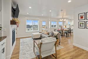 Living room with a wealth of natural light, an inviting chandelier, and light wood-type flooring