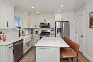 Kitchen featuring a breakfast bar area, appliances with stainless steel finishes, hardwood / wood-style flooring, and a kitchen island