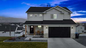 View of front of property with a garage, a yard, and a porch