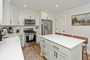 Kitchen featuring a kitchen bar, appliances with stainless steel finishes, tasteful backsplash, sink, and a center island