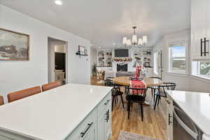 Kitchen featuring white cabinets, a kitchen island, decorative light fixtures, built in shelves, and stainless steel dishwasher