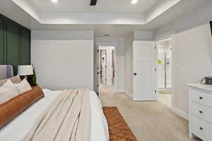 Primary Bedroom with light colored carpet and a tray ceiling