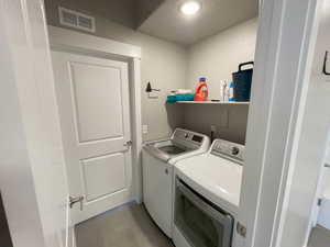 Laundry area with a textured ceiling, light tile patterned floors, and washing machine and clothes dryer