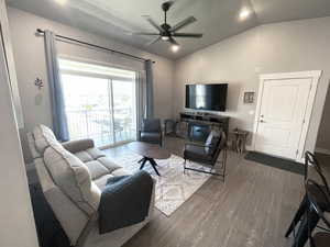 Living room featuring lofted ceiling, ceiling fan, and dark wood-type flooring