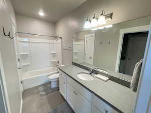 Full bathroom featuring toilet, vanity, tub / shower combination, and tile patterned floors