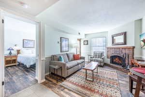 Living room featuring tile patterned floors, a brick fireplace, and a textured ceiling