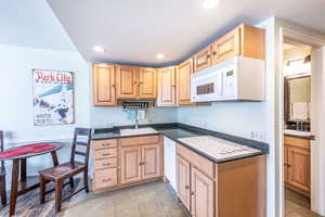 Kitchen with sink, white appliances, a textured ceiling, and light tile patterned flooring