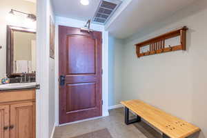 Doorway to outside with sink, a textured ceiling, and light tile patterned floors