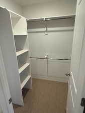 Walk in closet featuring light colored carpet