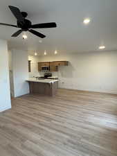 Kitchen with ceiling fan, kitchen peninsula, stainless steel appliances, and light hardwood / wood-style floors