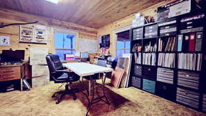 Carpeted home office with wood ceiling and wooden walls
