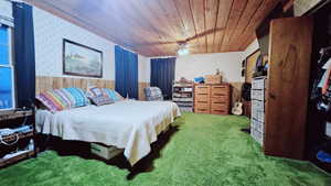 Bedroom with ceiling fan, wooden ceiling, carpet, and wooden walls