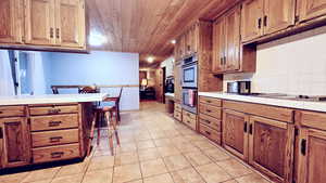 Kitchen featuring tile countertops, wooden ceiling, a breakfast bar area, backsplash, and light tile patterned flooring