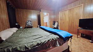 Bedroom with light colored carpet and wooden walls