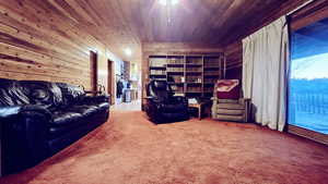Carpeted living room featuring ceiling fan, wood ceiling, and wood walls