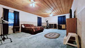 Bedroom featuring wooden ceiling, carpet, wood walls, and ceiling fan