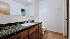 Bathroom featuring toilet, vanity, and tile patterned floors