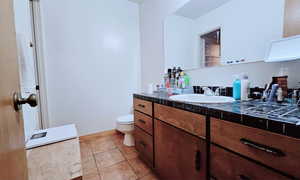 Bathroom with toilet, tile patterned floors, and vanity