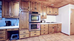 Kitchen featuring wooden ceiling, gas stovetop, backsplash, and stainless steel double oven