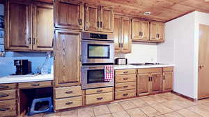 Kitchen featuring light tile patterned floors, wood ceiling, stainless steel double oven, tasteful backsplash, and white gas stovetop