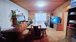 Carpeted dining area with wood walls and wood ceiling