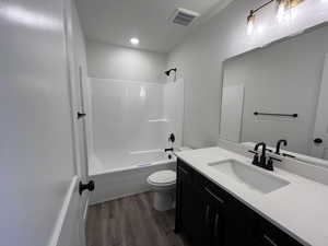 Full bathroom with wood-type flooring, toilet, vanity, and shower / washtub combination