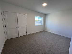 Unfurnished bedroom with a closet and dark colored carpet