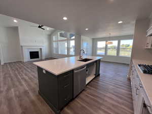 Kitchen with decorative light fixtures, white cabinetry, stainless steel appliances, an island with sink, and sink