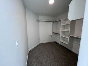 Walk in closet featuring dark colored carpet