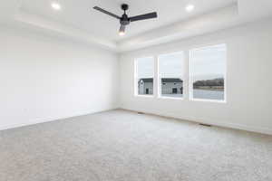 Spare room with ceiling fan, carpet flooring, and a raised ceiling