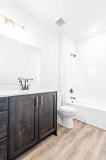 Full bathroom with vanity, wood-type flooring, shower / washtub combination, and toilet