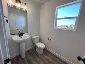 Bathroom with toilet, hardwood / wood-style floors, and sink