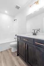 Full bathroom with vanity, hardwood / wood-style flooring, shower / bathtub combination, and toilet