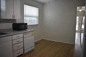 Kitchen with white dishwasher, hardwood / wood-style flooring, white cabinets, and ceiling fan