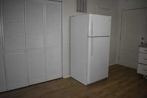 Kitchen featuring white cabinetry, hardwood / wood-style floors, and white refrigerator