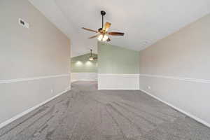 Carpeted spare room featuring ceiling fan and lofted ceiling