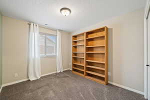 Unfurnished bedroom featuring dark carpet, a closet, and a textured ceiling