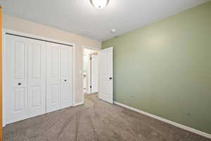 Unfurnished bedroom with carpet floors, a textured ceiling, and a closet