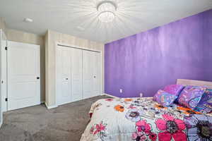 Bedroom featuring a textured ceiling, a closet, and carpet flooring