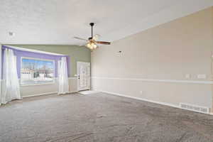 Spare room with a textured ceiling, ceiling fan, carpet, and lofted ceiling