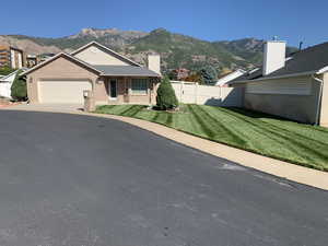 View of front of house with a front lawn, a mountain view, and a garage