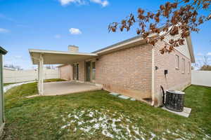 Rear view of property with a lawn, central AC, and a patio area