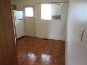 Interior space with white fridge and dark tile patterned floors