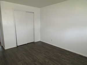 Unfurnished bedroom with a closet and dark wood-type flooring