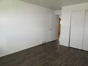 Unfurnished bedroom featuring dark wood-type flooring and a closet