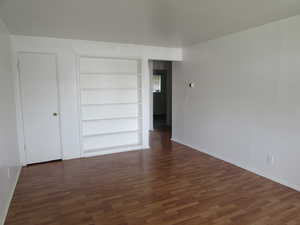 Empty room with dark wood-type flooring and built in shelves