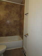 Bathroom featuring tile patterned floors, toilet, and tiled shower / bath