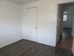 Unfurnished bedroom featuring dark wood-type flooring